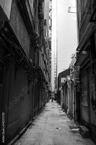 Hong Kong narrow street. Scary black and white photography of a very narrow and dirty street in the city center of HK. Vertical composition shot.