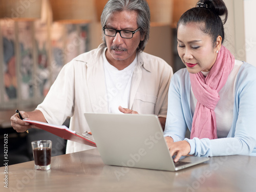 Asian senior couple using laptop sitting in room work from home. Technology and communication