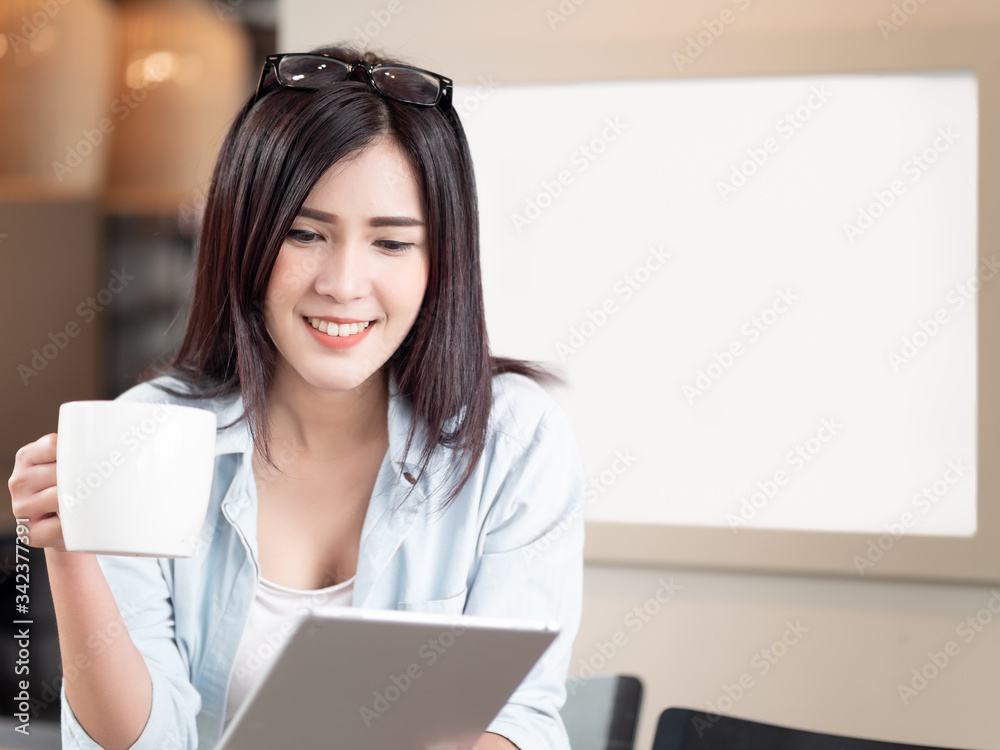 Beautiful asian woman using digital tablet and drink coffee while sitting at home with copy space. Lifestyles and Technology Beautiful asian woman using digital tablet and drink coffee while sitting at home with copy space. Lifestyles and Technology
