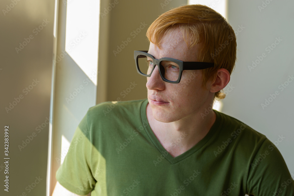 Face of nerd man with red hair looking out the window