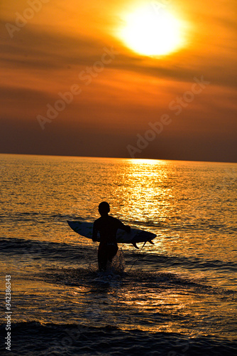 silhouette of a man Surfing in the sunset