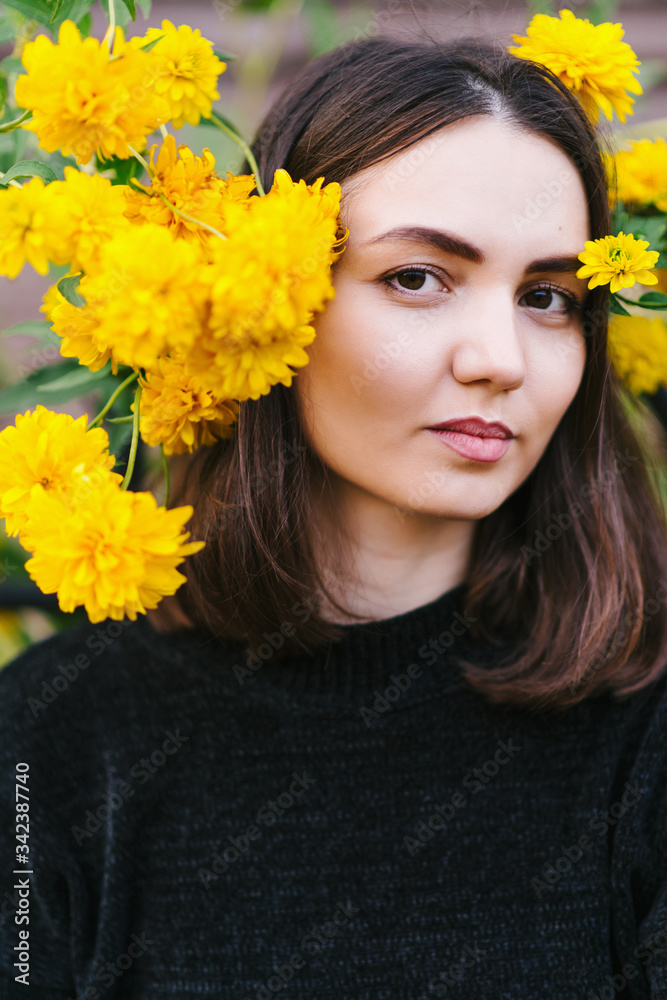 Beautiful girl in a black sweatshirt and with yellow flowersм Beautiful girl in a black sweatshirt and with yellow flowersм