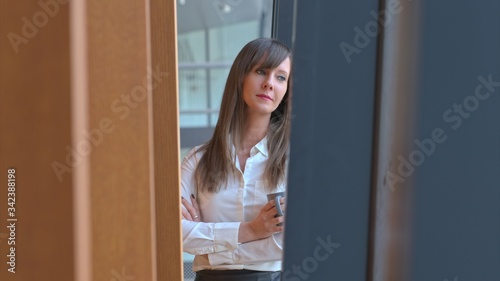 Free Download Businesswoman taking break in office drinking coffee standing in window and daydreaming, thinking. - GFXLoad