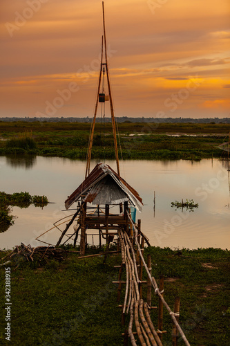 Traditional fishing tool or bamboo fish trap on sunset light, landscape silhouette.