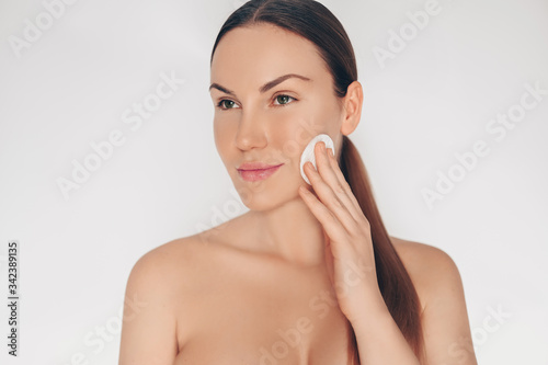 Close up portrait of beautiful half naked natural beauty woman cleansing face perfect skin isolated white background. Cleaning healthcare treatment. Skincare spa concept. Space for text mockup