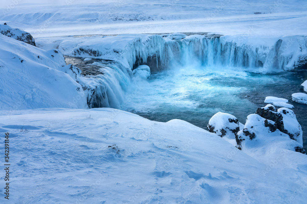 Half frozen Icelandic river Skjalfandafljot flowing over the waterfall Godafoss in Winter