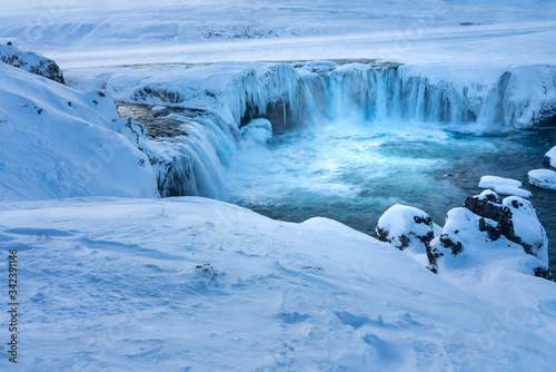 Half frozen Icelandic river Skjalfandafljot flowing over the waterfall Godafoss in Winter