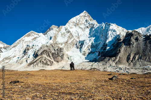 Young couple watching at Mount Mt. Everest and Nuptse peak at Kala Pattar. Trekking in Nepal Himalayas. EBC (Everest base camp trek) trail upper part from Lukla to EBC of Everest trek. Nepal.