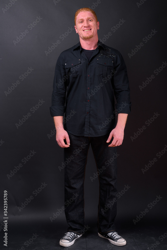 Full body shot of happy muscular man with orange hair smiling Full body shot of happy muscular man with orange hair smiling