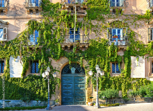 facade detail of city hall building in the historic center of Agrigento overgrown with ivy, door and windows and decoration. Agrigento Sicily. Italy © poludziber