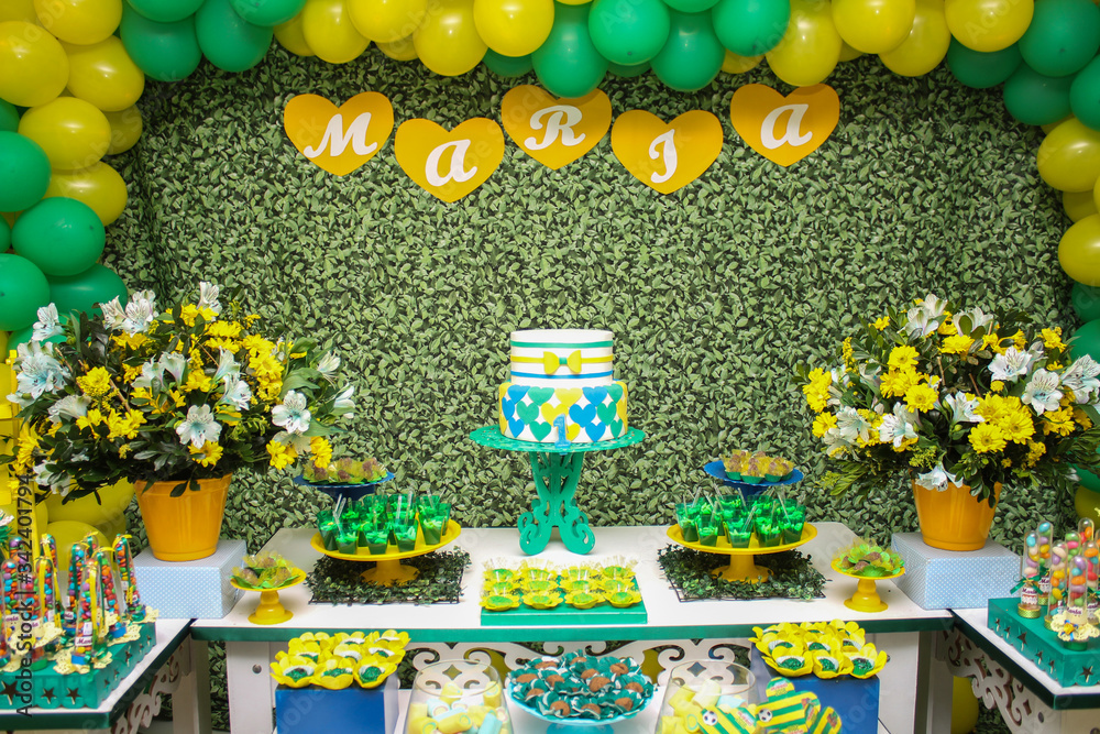 Birthday Setup. Cake table with sweet, decoration and flowers. Party with the colors of Brazil. Green, yellow, blue and white