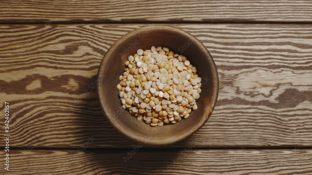 Dried yellow peas fill a wooden dish. Top view, stop motion. Dried yellow peas fill a wooden dish. Top view, stop motion.