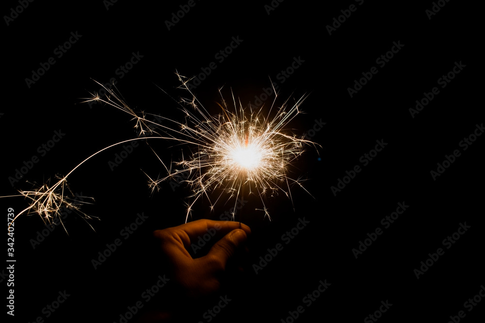 hand holding firework sparkles with light trail with bright orange light with black isolated background