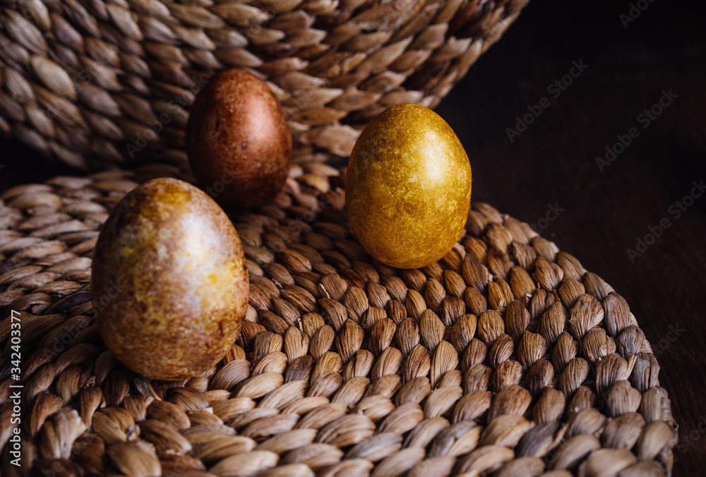 golden eggs on wicker natural background, easter eggs, unusual stylish food design