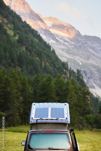 Back view of open back door of hatchback car in forest. Selective view of vehicle, breathtaking scenery with mountains on background, nice sunny summer day. Tourism in Alps. photo