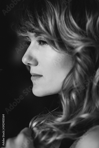 Portrait of a 36 year old woman with curly hair and brown slanting eyes. Soft selective focus. Black and white art photo.