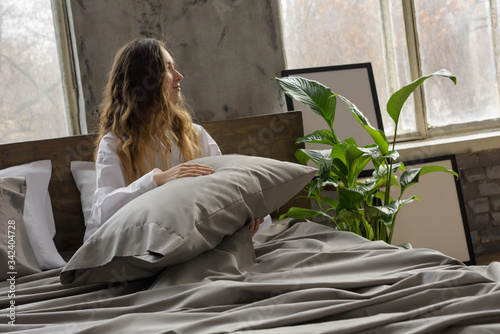 woman in bed, woman hugging pillow, window in the interior photo