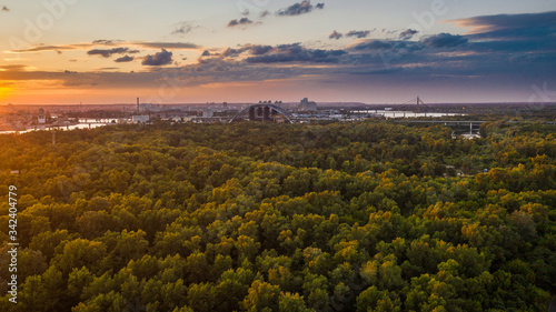 An aerial view is taken with a drone of sunset on summer time in Kyiv (Kiev) city. Skyline with a bridge in construction above the Dniepr river.