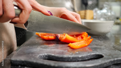 housewife with red manicure cuts Bell pepper on black cutting board making salad for lunch extreme close view