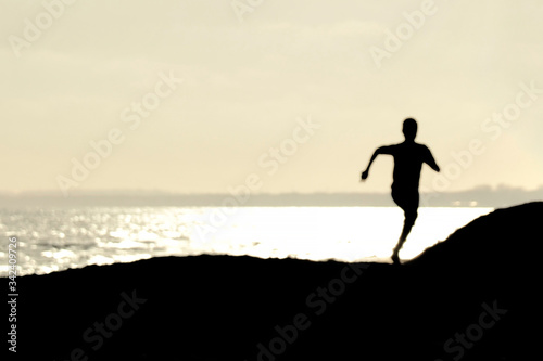 Backlight of a boy running on the beach at sunset with the horizon in the background. Freedom and youth concept.