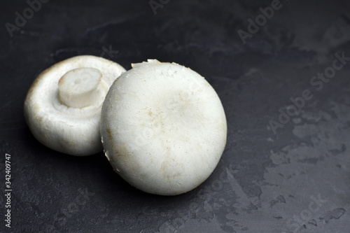 Two champignon mushrooms on black background. Vegan food concept. Copy space.