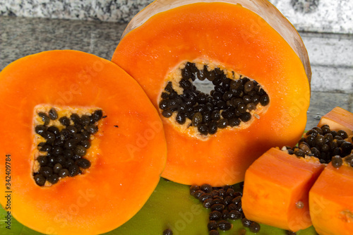 Delicious sweet orange papaya fruit cut on pieces on a green cutting board