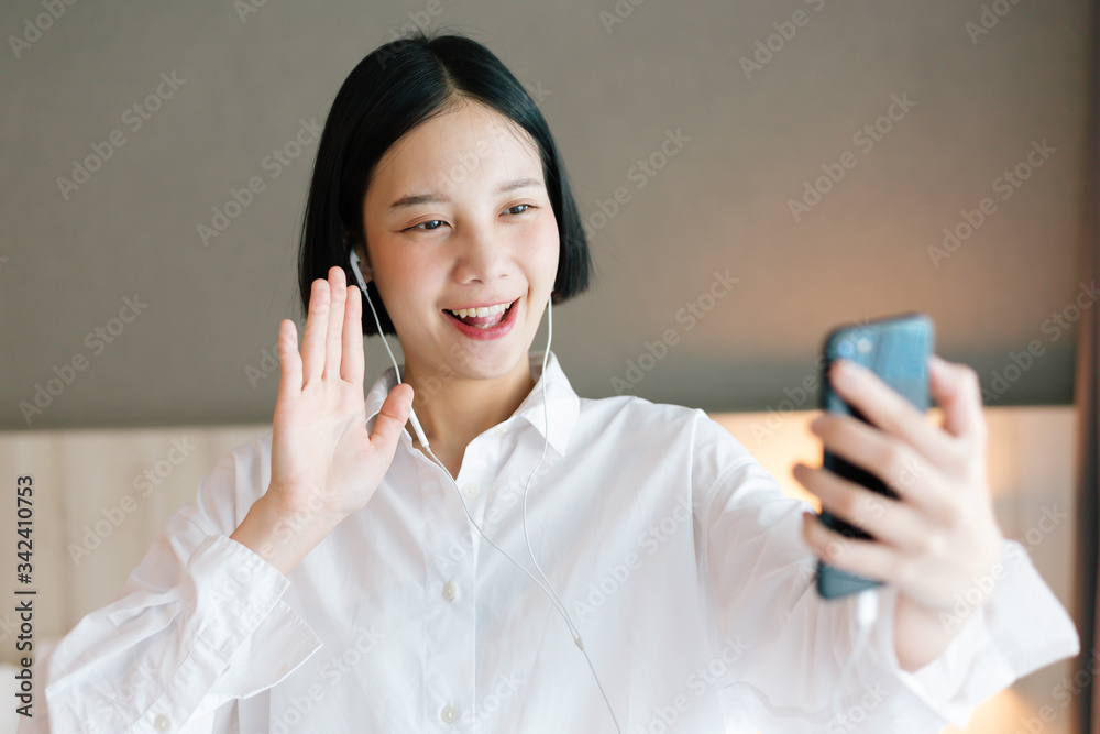 Beautiful asian female in white shirt calling mobile phone while working on bed. work from home concept. Beautiful asian female in white shirt calling mobile phone while working on bed. work from home concept.