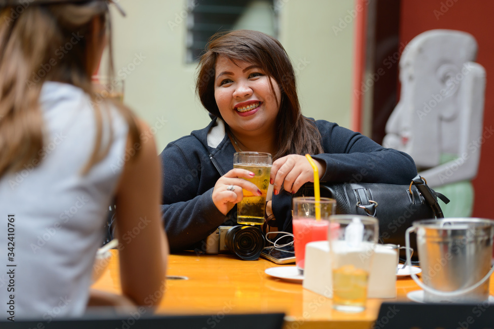 Happy young Asian women as friends hanging out and drinking beer outdoors