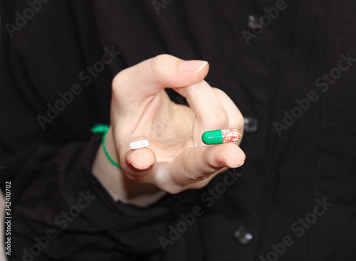 On the fingers of the hand are two different tablets. Choice of medicine or vitamins.