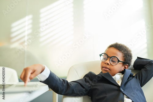 Junge als Geschäftsmann sitzt entspannt im Büro