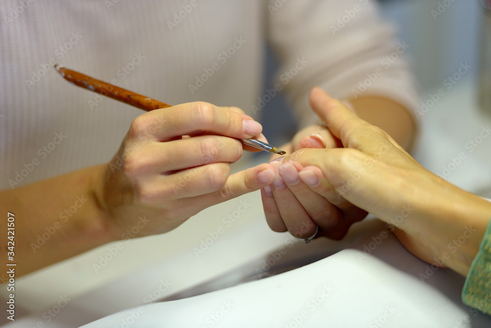 Hands of woman manicurist and customer showing manicure procedure