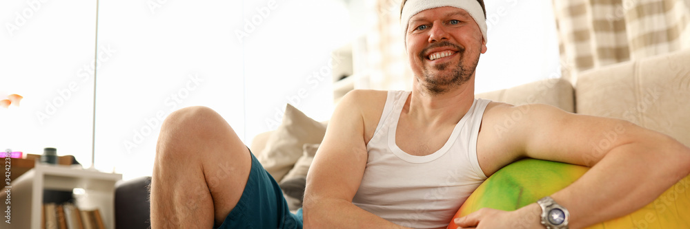 Man sitting at home carpet near ball and dumbbells Man sitting at home carpet near ball and dumbbells