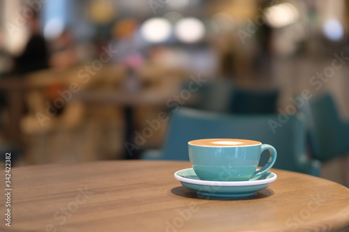 close up a cup of coffee on wooden table in cafe. colorful bokeh background
