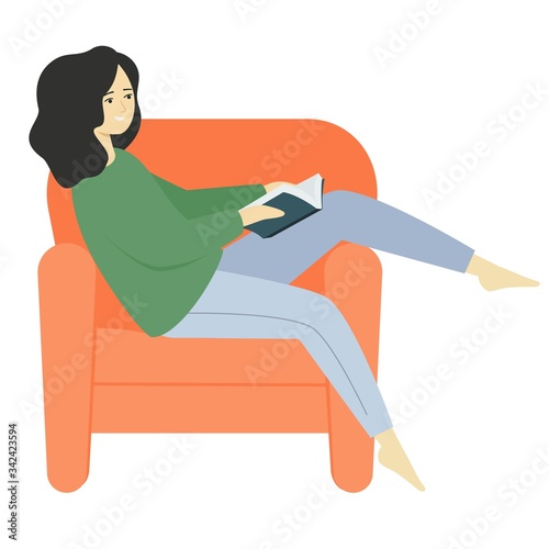 Cute girl is reading a book. A young woman sits in an armchair with her foot on the armrest.