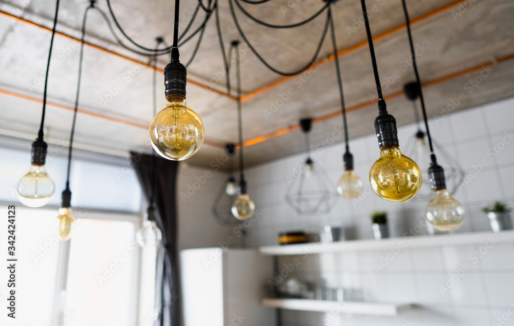 Big vintage incandescent light bulbs hanging in modern kitchen. Decorative antique edison light bulbs with straight wire. Inefficient filament light bulbs waste electricity. E27, dimmable, warm white