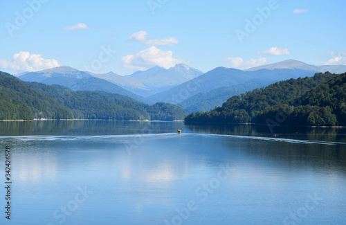 A small pleasure boat crosses the Vidraru lake  hydropower construction  in the Carpathian Mountains  Transfagarasan  Romania 