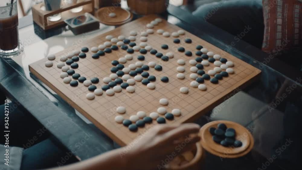 Close up view of hands young people playing go board game in living room
