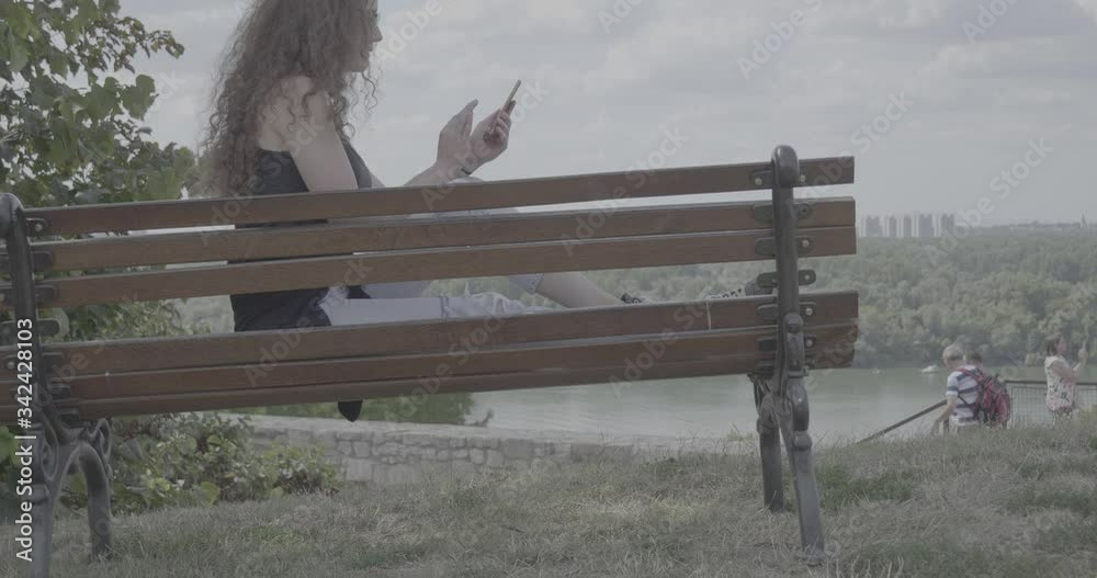 Close up of smiling girl looking at camera, outdoor city view near the river. Curly hair fashion model face. Portrait side view. Female nature beauty. Shooting from the back. Camera rising up, s- log,