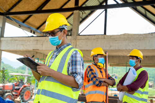 Engineer corporate workers wearing protective masks to prevent dust and covid 19 disease during the inspection in construction site,Coronavirus has turned into a global emergency. photo