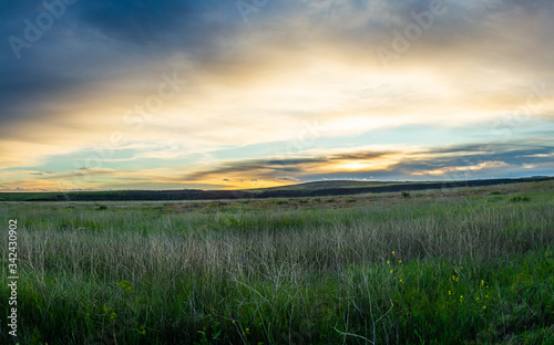 Sunrise over a green prairie with distant hills on Black Mesa in the Aqua Fria National Monument in Arizona.