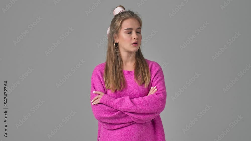 A displeased young woman is crossing her hands and showing resentment isolated over a grey background in studio A displeased young woman is crossing her hands and showing resentment isolated over a grey background in studio