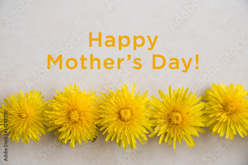 Happy Mothers Day. Yellow dandelions lies on a light textured surface. Wedding card. Flat lay, top view