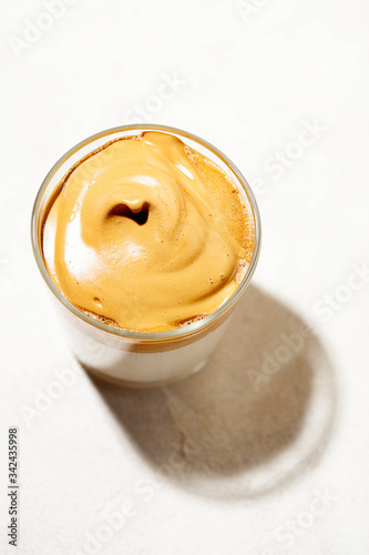 Trendy fluffy creamy whipped iced Dalgona coffee on white background.Korean drink latte espresso with foam of instant coffee