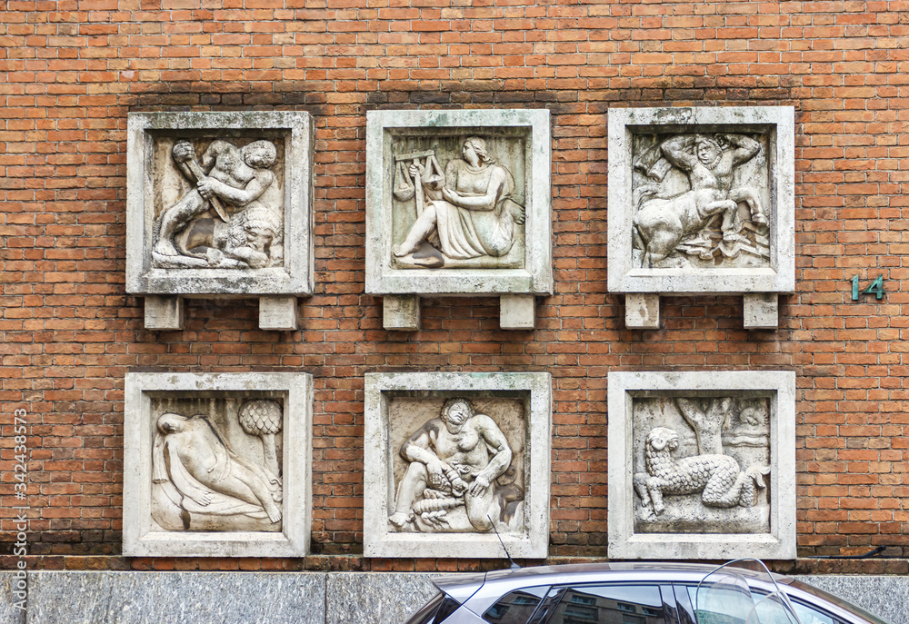 Stone bas-reliefs with the image of the zodiac signs on the wall of Teatro Romano theater building on Piazza degli Affari square in Milan, Italy.