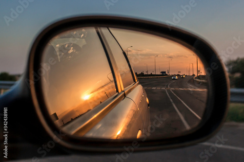 Sunset reflection in the car mirror on the road in summer 