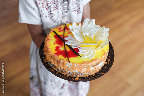 Beautiful yellow cake with white chocolate flowers in the child 's hands. Birthday cake. House birthday