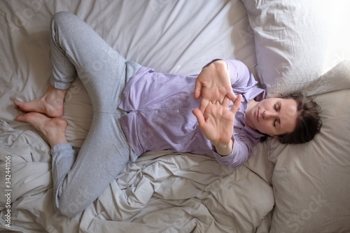woman doing supta baddha konasana on bed in the morning warming up
