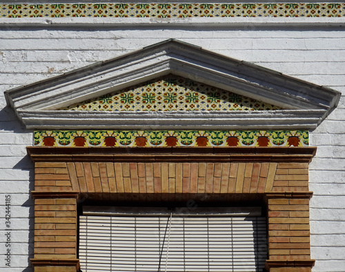 Detail of window with bricks and colorful tiles decoration and pediment in the top. City of Ronda. Andalusia. Spain.  