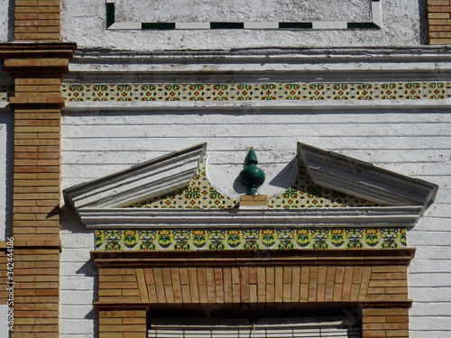 Detail of window with bricks and colorful tiles decoration and pediment in the top. City of Ronda. Andalusia. Spain.  