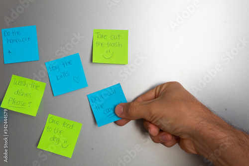 Reminders taped to fridge door and hand holding to read them photo